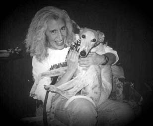 Black and white photo of Charlotte cuddling her Greyhound, Giselle, on her lap.